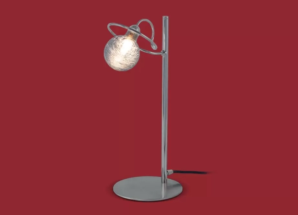 La lámpara de mesa Luciana II es un velador de metal de estilo moderno, se encuentra disponible en color cromo o en negro con bronce