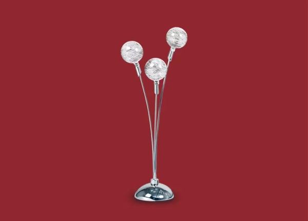 La lámpara de mesa Luciana es un velador de metal de tres luces apto LED, la cual se encuentra disponible en color cromo.
