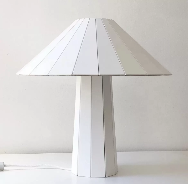 La lámpara de mesa Maja es una luminaria de diseño realizada en placas laqueadas. Disponible en blanco, negro o amarillo y dos tamaños.