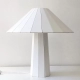 La lámpara de mesa Maja es una luminaria de diseño realizada en placas laqueadas. Disponible en blanco, negro o amarillo y dos tamaños.