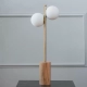 Lámpara de mesa Leia. Luminaria de estilo nórdico y moderno con base de madera paraíso maciza y estructura metálica con tulipas de vidrio opal. Color bronce